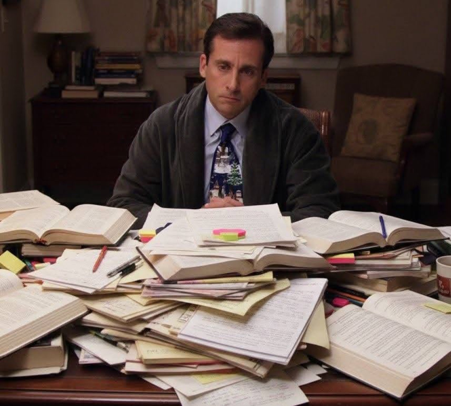 Michael Scott sitting behind a desk buried in papers and books