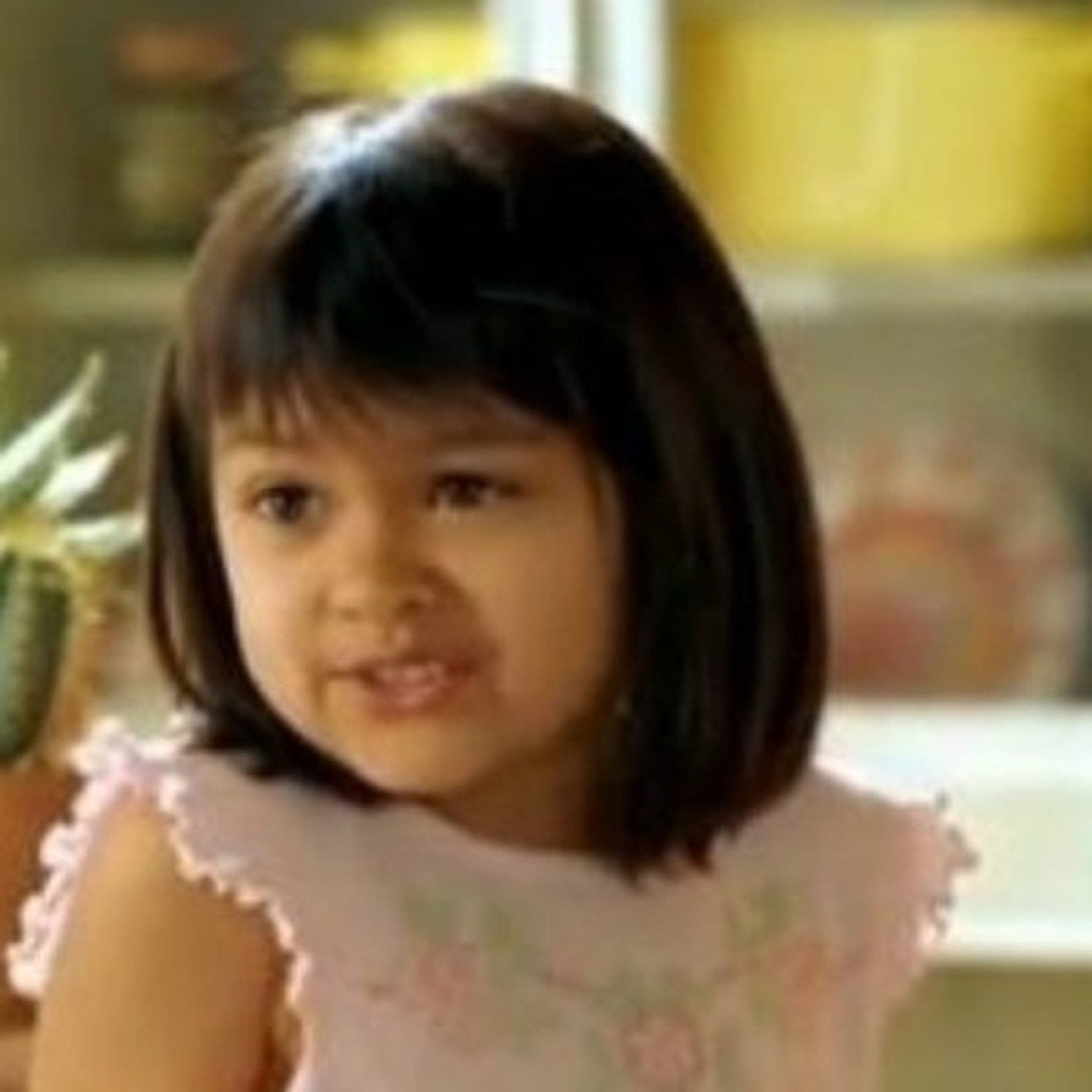 Little girl in a pink dress with a sly, knowing smirk