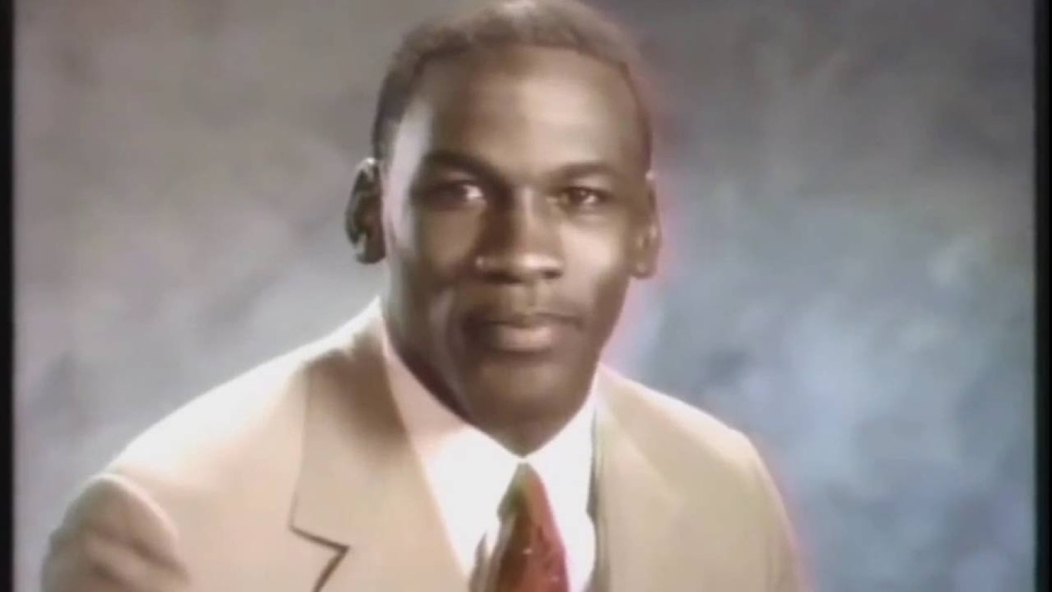 Man in a tan suit smirking confidently at the camera in an old portrait