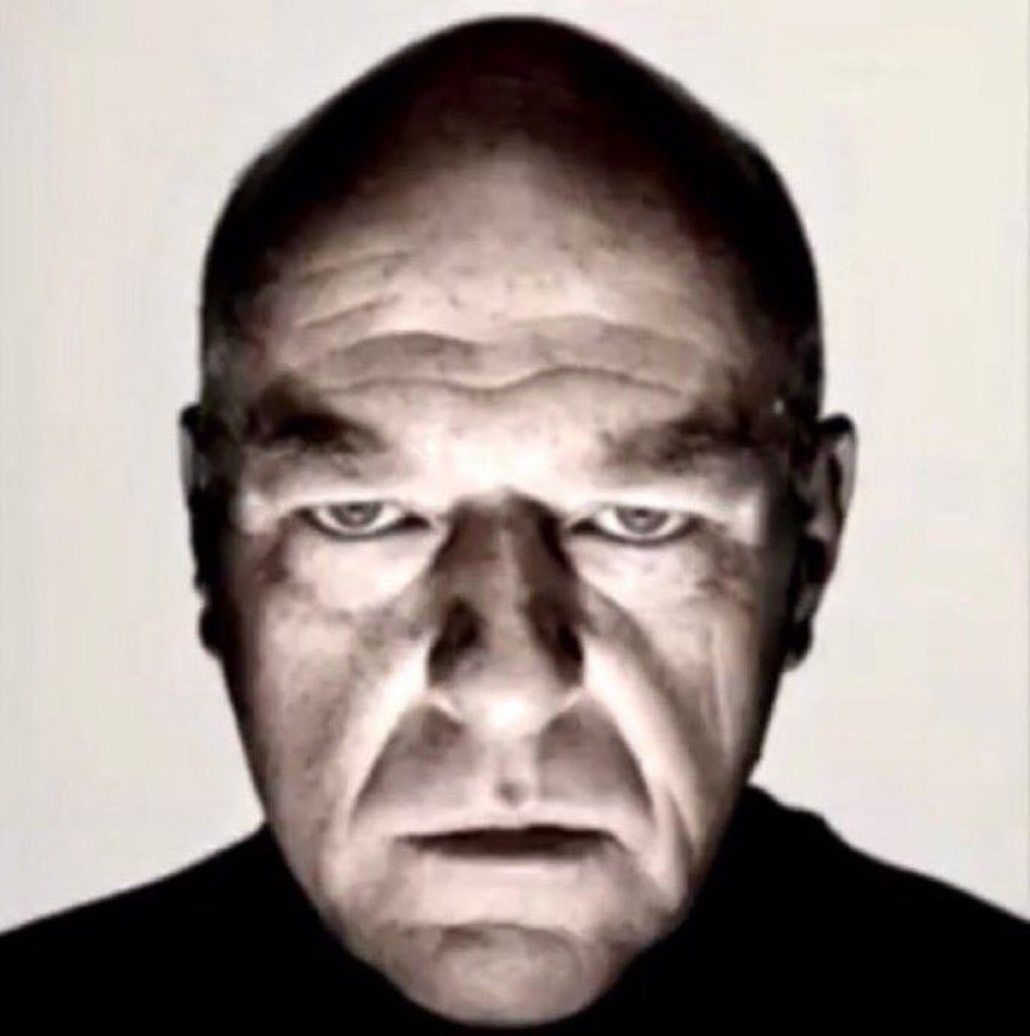 Bald man in high-contrast black and white, glaring intensely at the camera