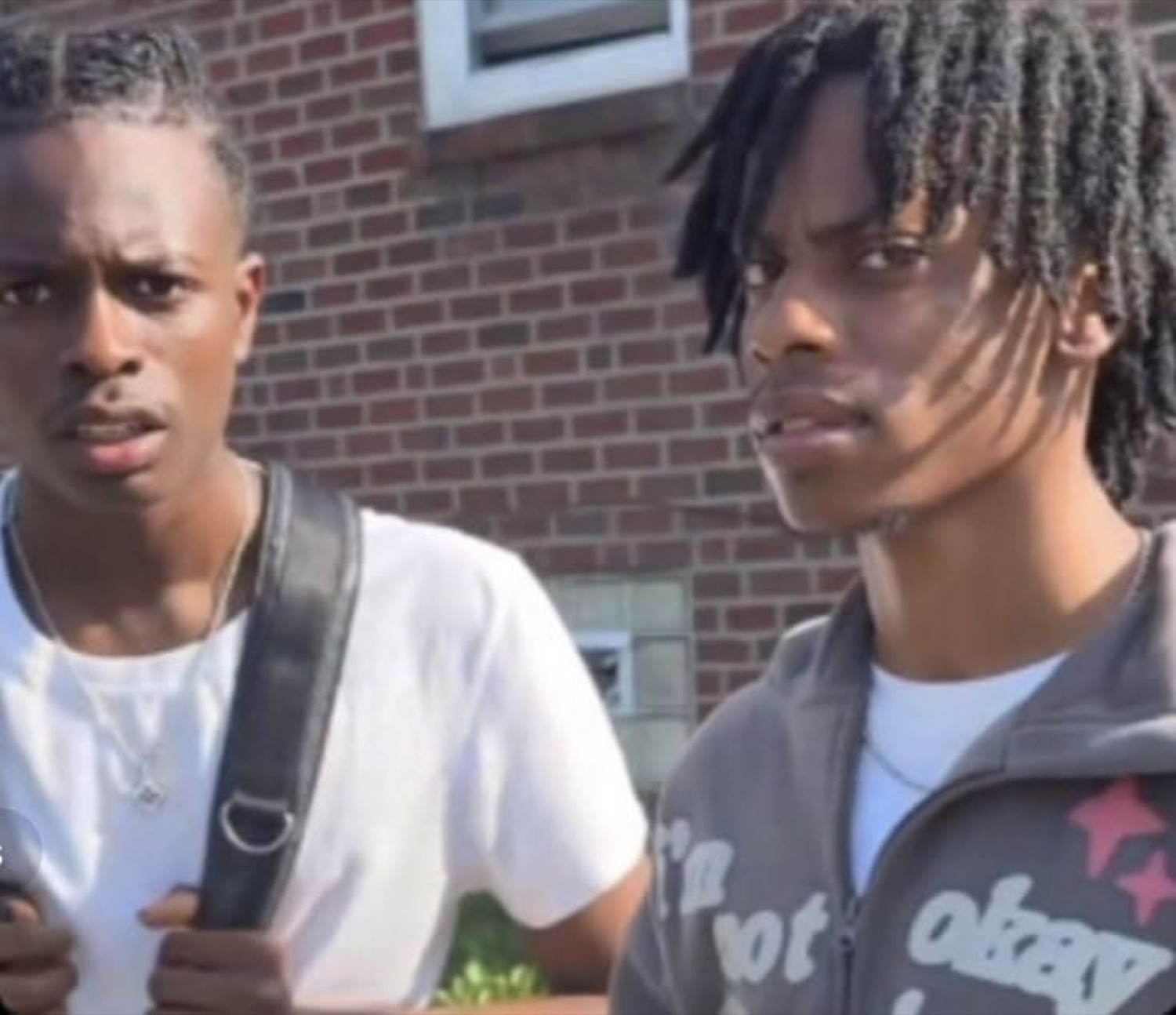 Two young men standing side by side with serious, skeptical expressions