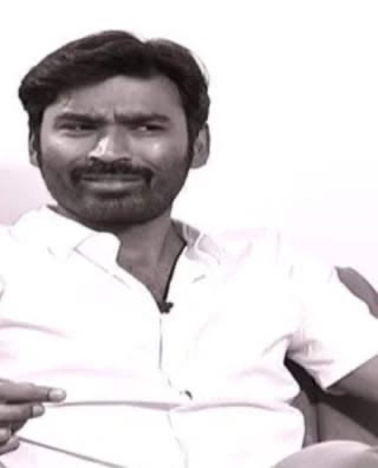 Dhanush sitting with a deadpan side glance