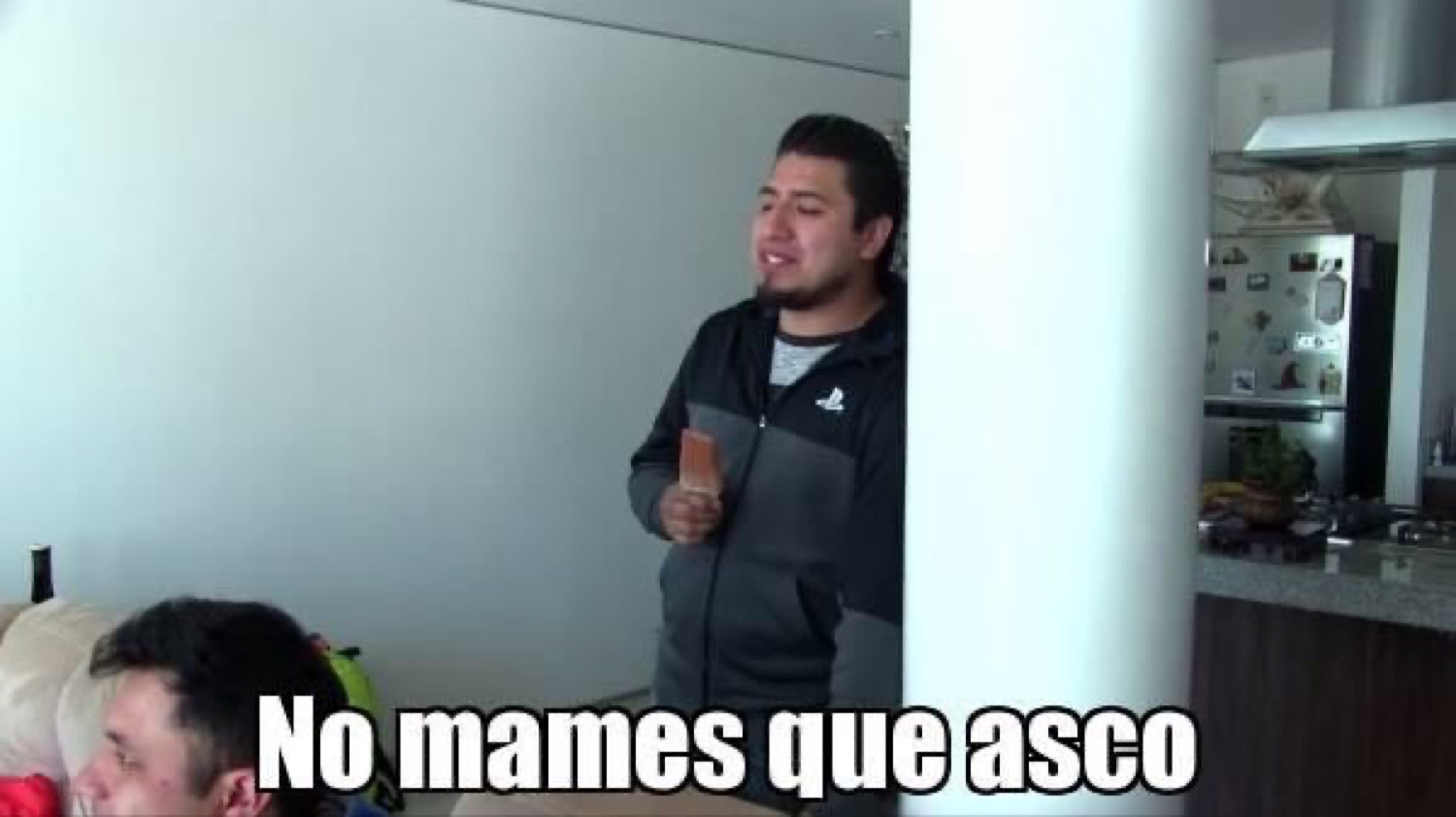 Man standing in a living room looking grossed out, captioned 'No mames que asco'