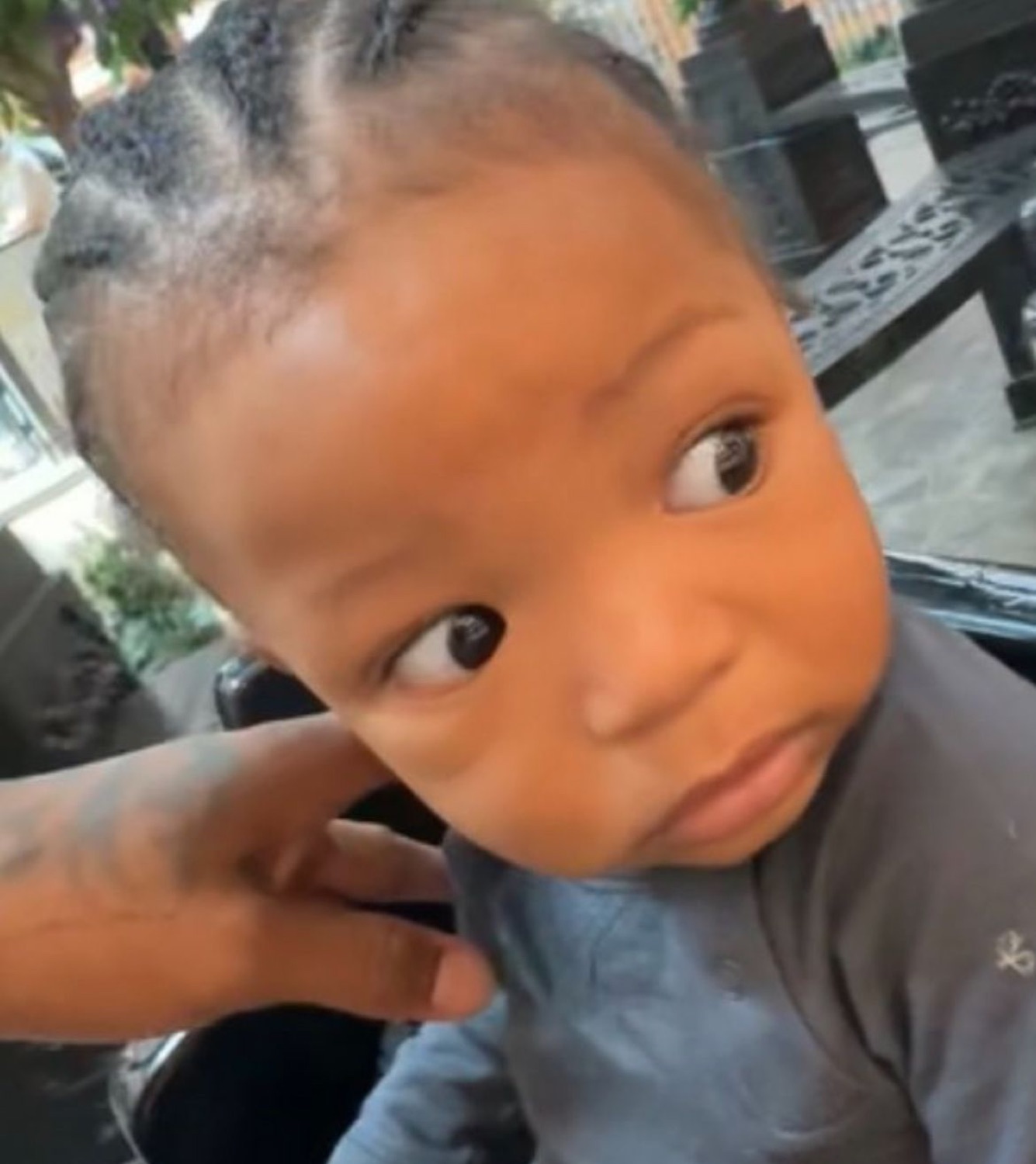Baby giving a wary sideways side-eye glance as a hand tugs at their ear