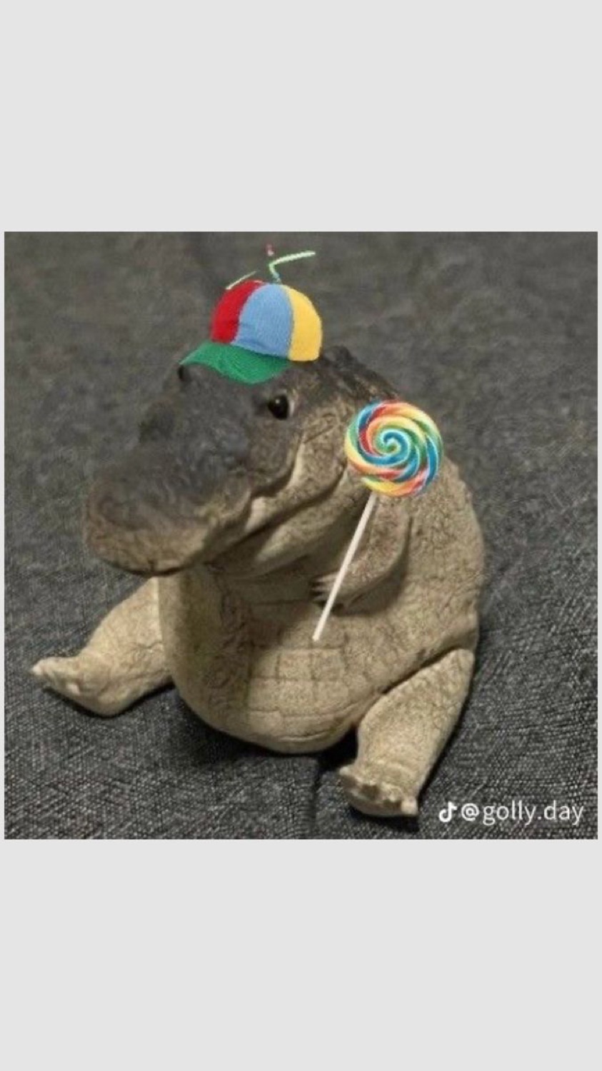 Chubby alligator figurine in a propeller hat holding a lollipop