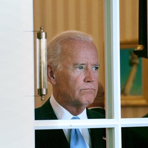 Joe Biden gazing wistfully out a White House window with a sad, faraway look