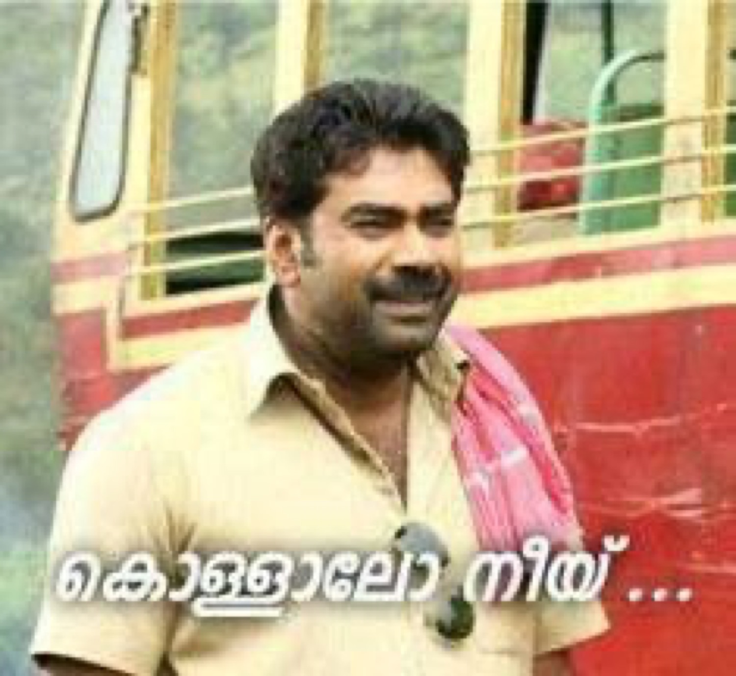 Man by a bus grinning: 'കൊള്ളാലോ നീയ്...' (not bad, you)