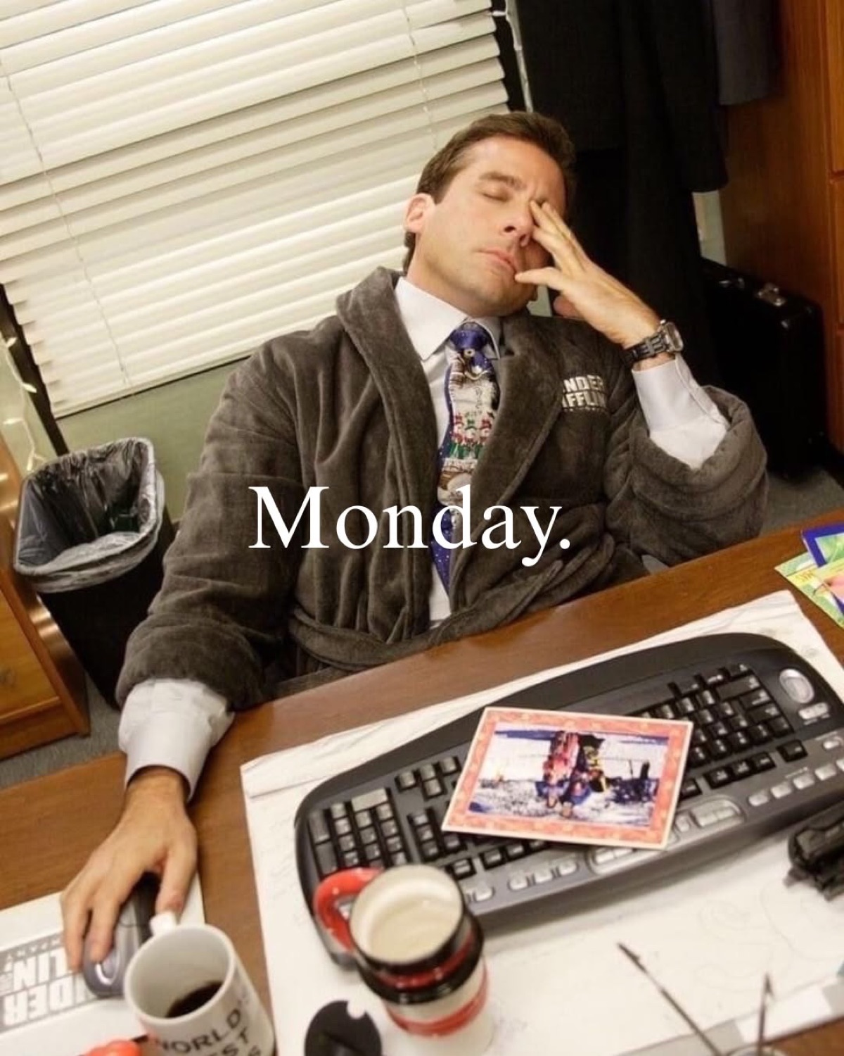 Michael Scott in a bathrobe slumped at his desk with a hand on his face, captioned 'Monday.'