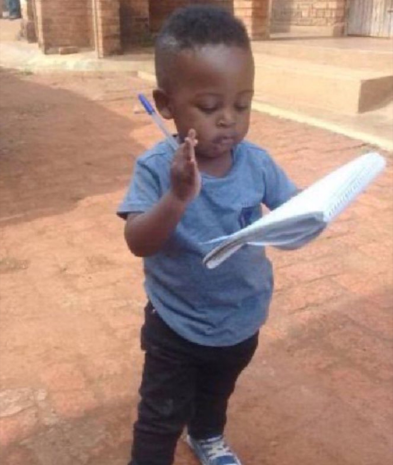 Toddler studying a sheet of paper with a pen, very serious