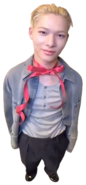 Blond guy with a red ribbon tied around him shot from above with a tight little smile sticker