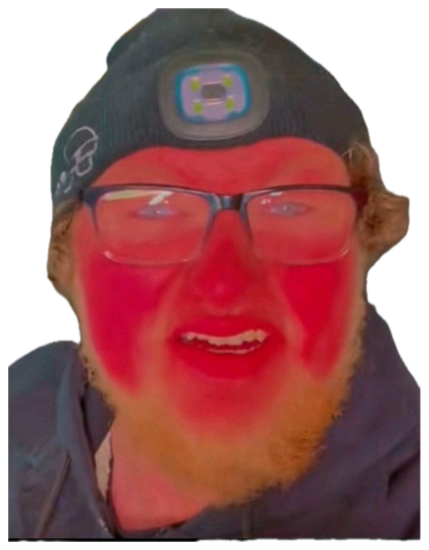 Man with red-flushed face filter grinning menacingly with a headlamp hat sticker