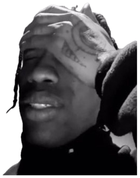 Black-and-white shot of a man with face tattoos smiling and rubbing his forehead sticker