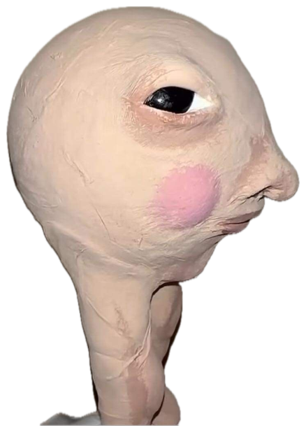 Bald, egg-shaped prosthetic head with one visible eye and a blushed cheek sticker