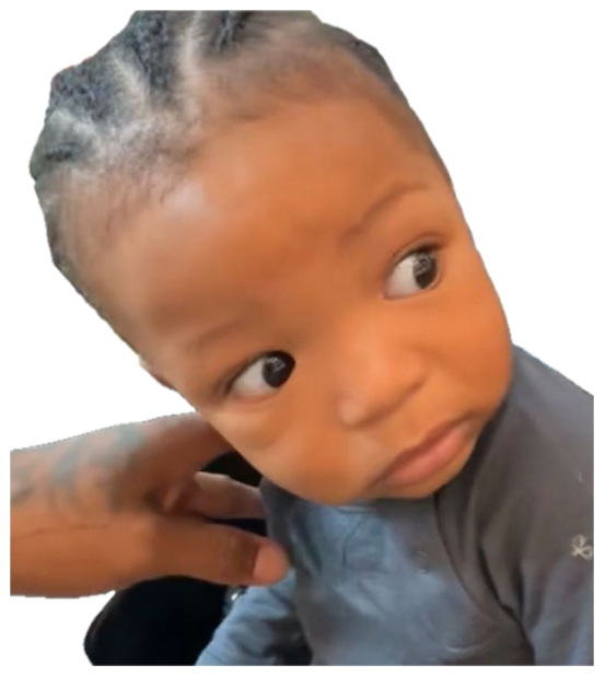 Baby giving a wary sideways side-eye glance as a hand tugs at their ear sticker